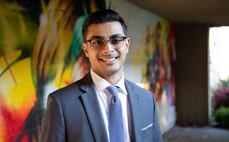 Student in suit in front of mural